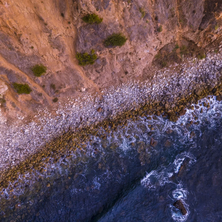 Aerial view of waves meeting a rocky coastline