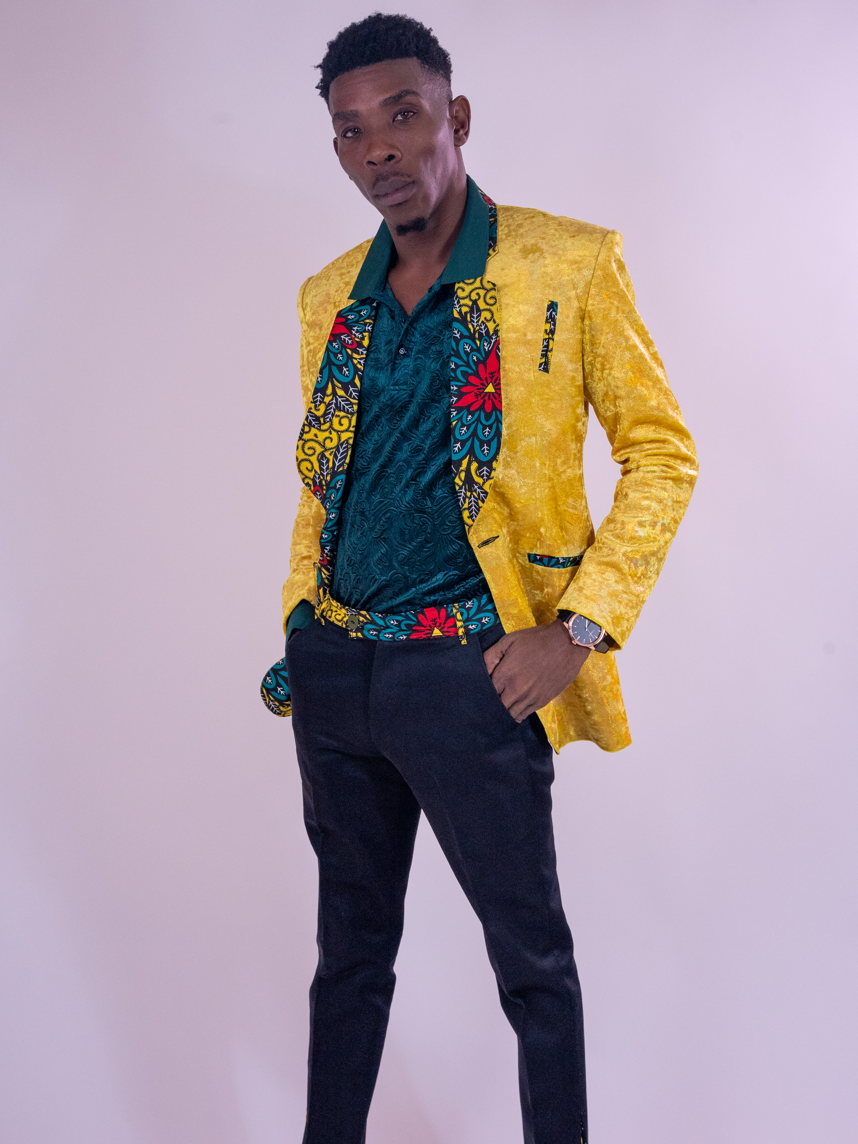 Standing portrait in a yellow jacket against a pale studio backdrop