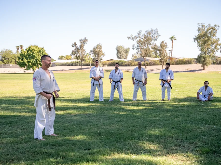 Martial artists lined up in a sunlit park