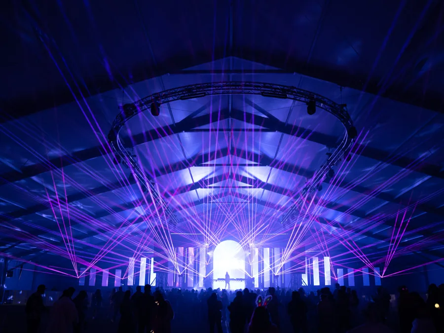 Blue and violet beams illuminating an event tent