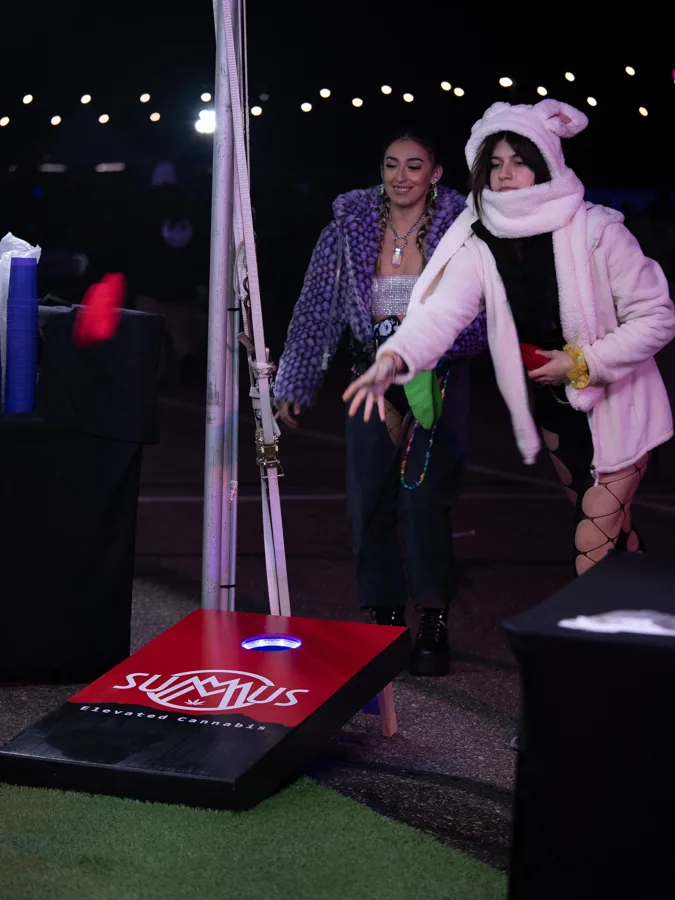Two guests playing cornhole at an evening event